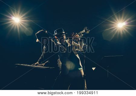 Musician Duo band playing a Trumpet and keyboard on black background with spot light and lens flare musical concept