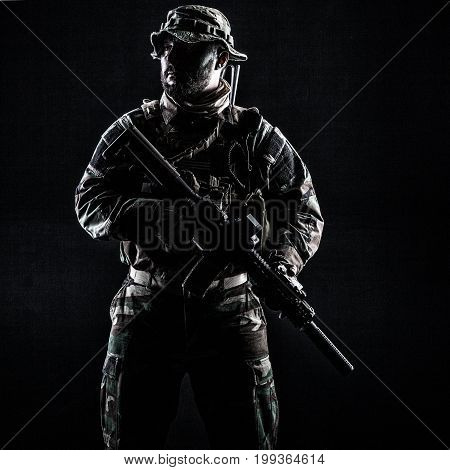 Bearded Special forces United States in Camouflage Uniforms studio shot half length. Holding weapons, wearing jungle hat, Shemagh scarf, he is ready to kill. Contour shot, backlit