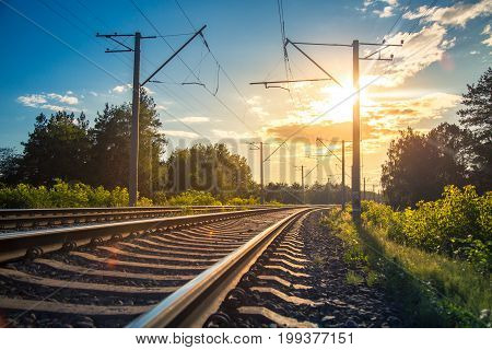 Industrial landscape with rails and railway. Railroad leaving into the distance against the sunset