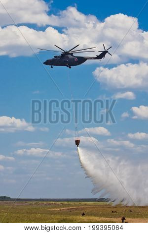 Russian firefighting helicopter with waterbag dropping water on fire extinguishing training