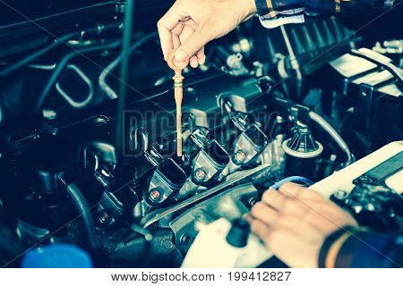 Close up hands checking lube oil level of car engine from deep-stick for service and maintenance concept.