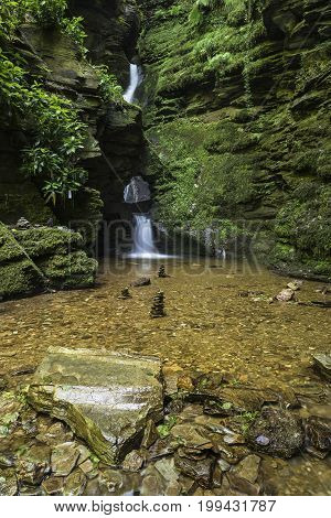 Beautiful Flowing Waterfall With Magical Fairytale Feel In Lush Green Forest Location