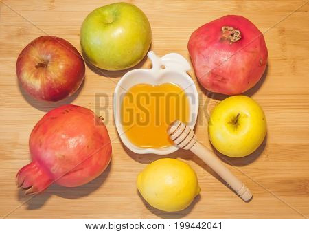 Fresh apples and pomegranates with sweet honey at the table during the traditional Jewish holiday Rosh HaShanah (Jewish New Year) concept.