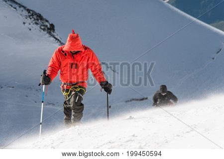 The climber climbs the snow-covered summit. The concept of overcoming difficulties and achieving the goal