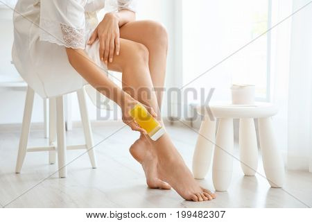 Beautiful young woman removing hair with wax at home