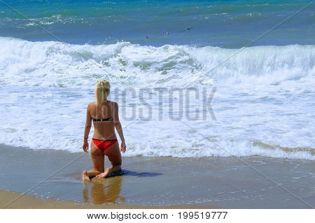 July, 2017 - A woman in a red swimsuit in the surf on the seashore at Cleopatra Beach (Alanya, Turkey).