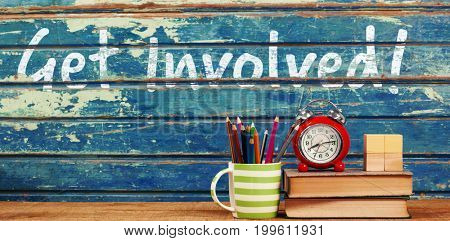 Get involved text against white background against books with alarm clock on table
