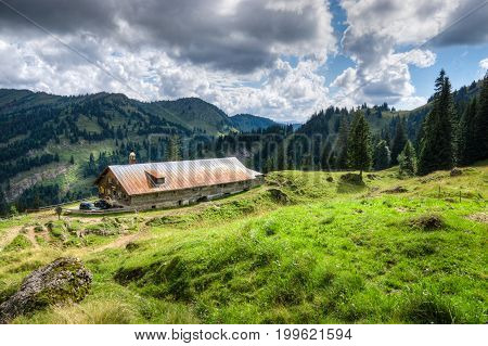 Old alpine hut with meadow in the Alps. Bavaria, Allgau, Germany. Traditional farming in the bavarian mountains.