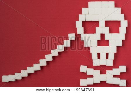 The skull made from sugar cubes. Sugar Kills. Red background. diabetes concept. Suggesting dieting concept. Unhealthy white sugar concept. Copy space. Space for text.