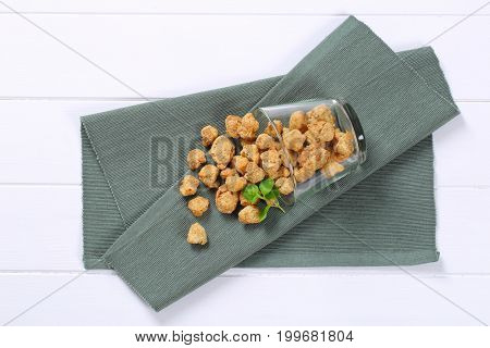 glass of soy meat cubes spilt out on grey place mat