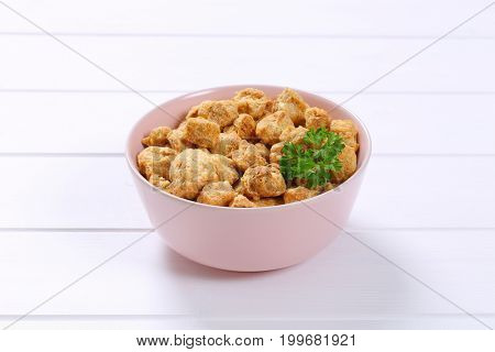 bowl of soy meat cubes on white wooden background