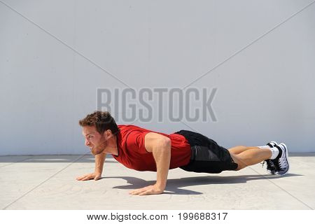 Pushup fitness man doing push-up bodyweight exercise on gym floor. Athlete working out chest muscles strength training outdoors