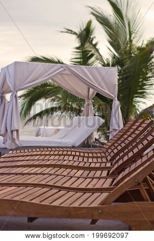 A row of wooden lounge chairs and a cabana.