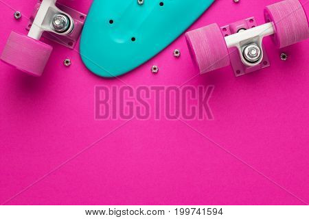plastic mini cruiser board disassembled. disassembled mini cruiser board on deep pink background. top view of disassembled plastic mini cruiser board. shot of mini cruiser board with copy space.