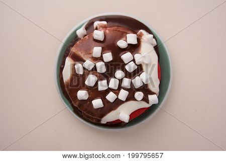 Top view of red pancakes with cream and marshmellows in plate isolated