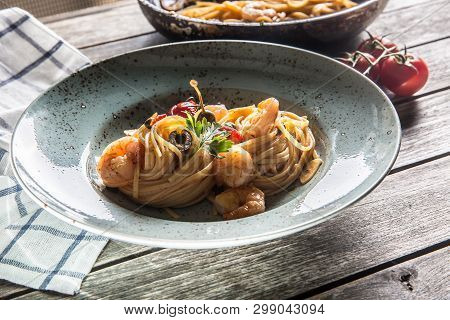 Pasta Spaghetti On Plate And Pan With Shrimp Tomato Sauce Toatoes And Herbs. Italian Or Mediterranea