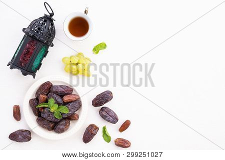 Ramadan Food And Drinks Concept. Ramadan Lantern With Tea, Dates Fruit, Grape And Mint Leaves On A W