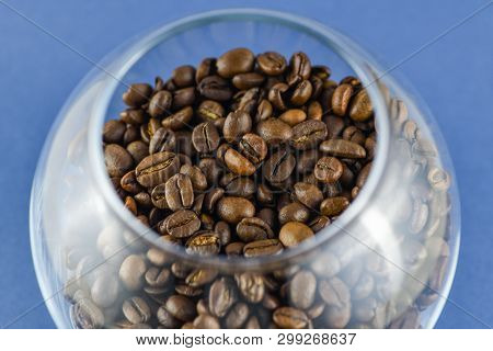 Close-up Top View Of Roasted Coffee Beans In A Glass Cup On An Blue Background