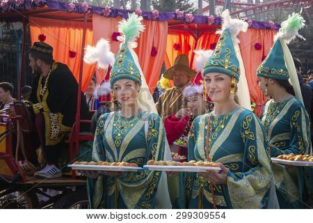 Almaty, Kazakhstan - March 21, 2019. Beautiful Girls In National Kazakh Clothes Are Holding Trays Wi