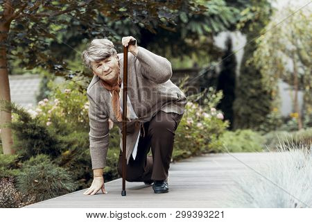 Sick Senior Woman With Walking Stick Waiting For Support After Chest Pain