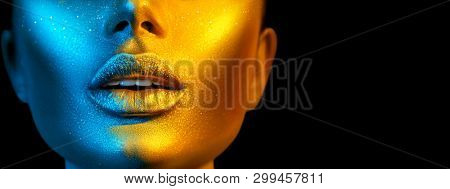 Fashion model woman skin face in bright sparkles, colorful neon lights, beautiful sexy girl lips, mouth. Trendy glowing gold skin make-up. Art design make up. Glitter metallic shine makeup Wide screen