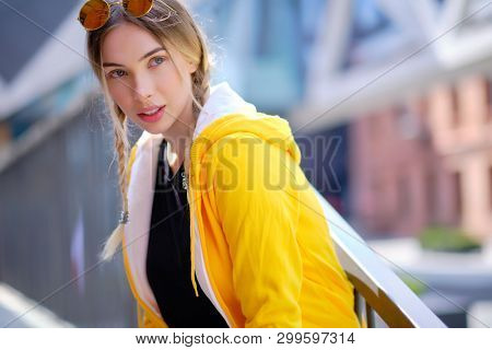 Portrait of blonde girl with flyaway hair in the street background 