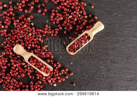 Lot Of Whole Peruvian Pink Pepper With Two Wooden Scoops Flatlay On Grey Stone