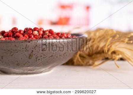 Lot Of Whole Peruvian Pink Pepper On Grey Ceramic Plate On Jute Cloth In A White Kitchen