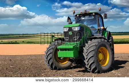 Russia, Krasnodar region, Kushevsky district.16.10.2018.   Modern, green tractor in the spring field work on the background of a beautiful rural landscape.