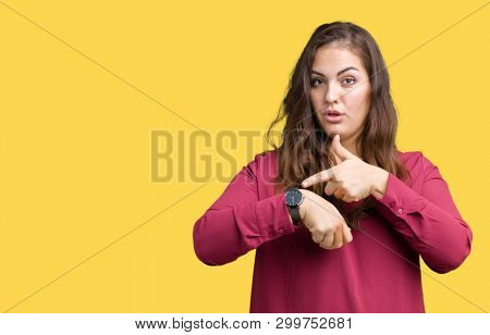Beautiful plus size young woman over isolated background In hurry pointing to watch time, impatience, upset and angry for deadline delay
