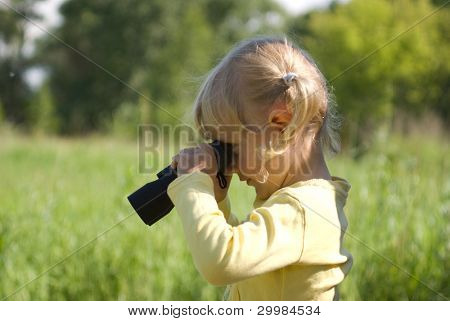 The little girl is looking through binoculars