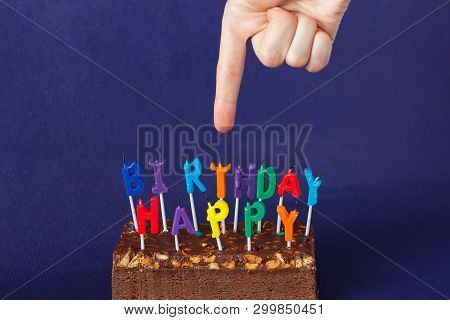 Hand Shows Happy Birthday Brownie Cake With Peanuts, Salted Caramel And Colorful Unlighted Candles O