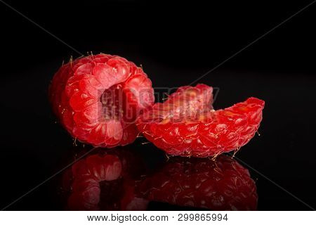 Group Of One Whole One Half Of Fresh Red Raspberry Isolated On Black Glass
