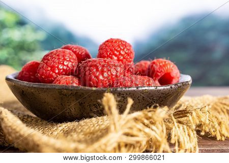 Lot Of Whole Fresh Red Raspberry On Grey Ceramic Plate On Jute Cloth In A Foggy Jungle Mountains