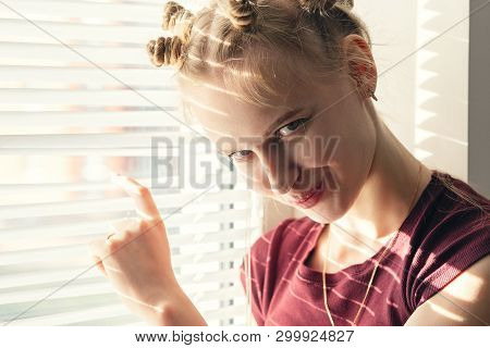Fun Shy Young Woman Near Window Blinds Looking At Camera Smiling