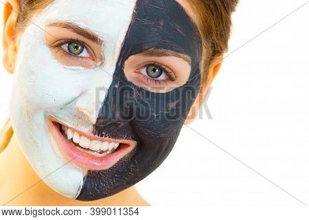Woman With Clay Carbo Black Mask On Half Face And White Mud On Second Half. Girl Taking Care Of Oily