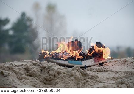 Burning Sports Sneakers Or Gym Shoes On Fire Stand On Sandy Beach Coast. Athlete Burned Out. Physica