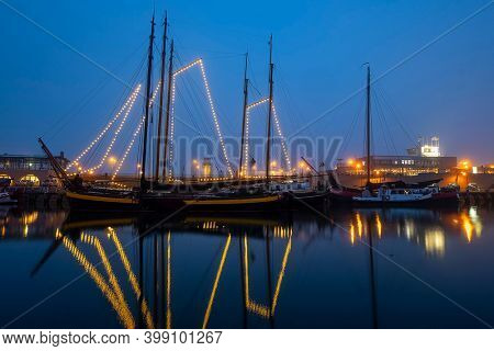 Decorated traditional sailing ship in the harbor from Harlingen in the Netherlands in christmastime at night