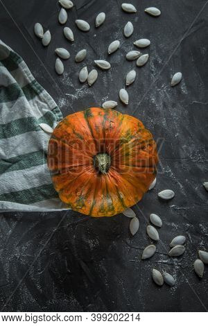 Beautiful Exquisite Small Pumpkin, On A Stone Table, Next To Pumpkin Seeds. Near Striped Towel. Top 