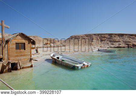 Wooden Boats Near The Sad Island. Nearby Is A Wooden House. Around The Blue Water. Heat Summer Egypt