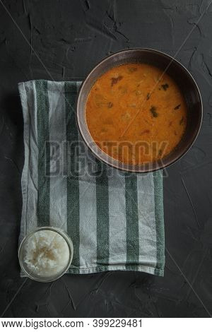 A Plate Of Tom Yam Soup On Towel Strips And Jar Of Rice . Top View