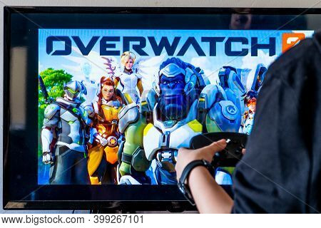 Woman Holding A Steam Controller And Playing Popular Video Game Overwatch On A Television And Pc