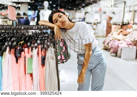 Tired woman at the rack in clothing store