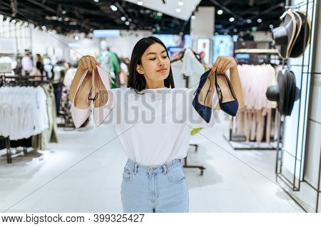 Cute woman choosing shoes in clothing store