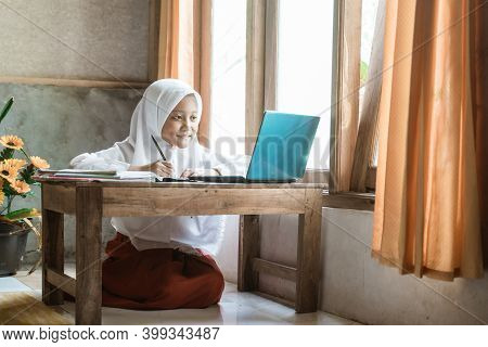 Indonesian Schoolgirl Studying Homework During Her Online Lesson
