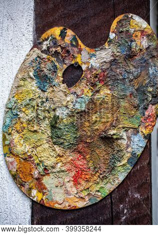Painter's Palette Covered In Mixed Vivid Paint Colors. An Abstract Painted Background