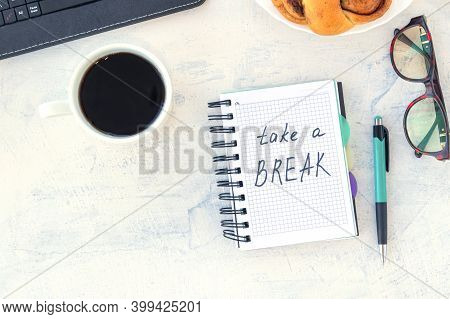 Take A Break. Concept Time Off. Words Take A Break In A Notebook On The Working Table With Cup Of Co
