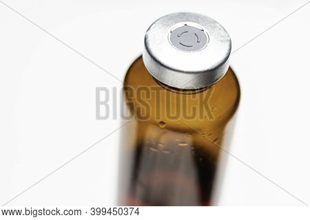 A Macro Shot With Selective Focus Of An Amber Color Vaccine Injection Bottle Set On Plain White Back