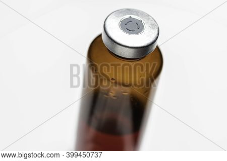 A Macro Shot With Selective Focus Of An Amber Color Vaccine Injection Bottle Set On Plain White Back