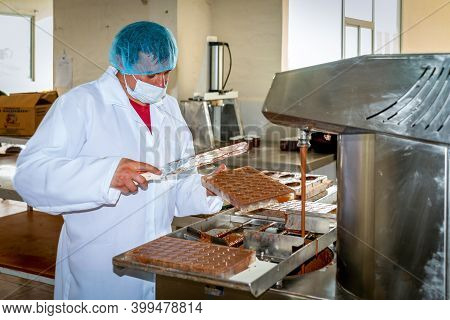 Guaranda, Bolivar / Ecuador - November, 2013: A Worker At A Local Chocolate Factory, In A White Coat